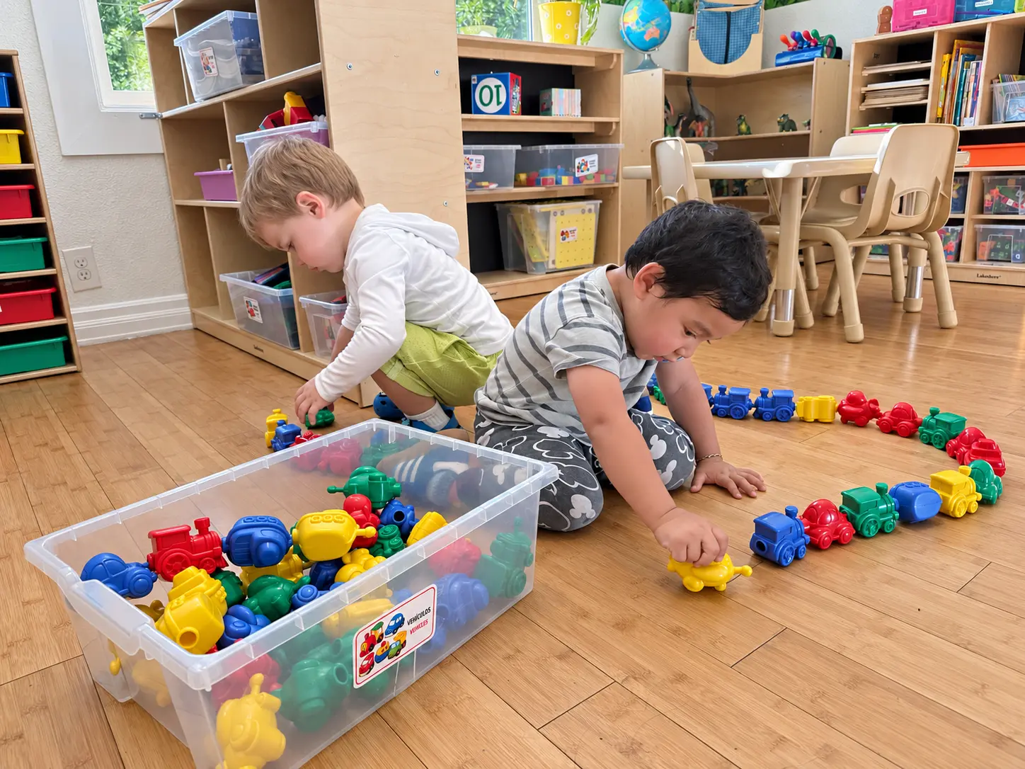 Two young children learning through play with colorful toy trains